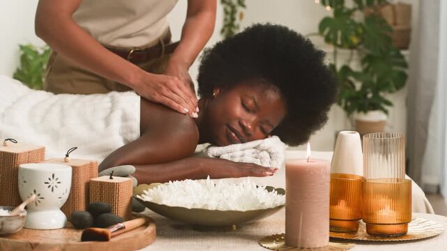 Serene Black Woman Relaxes During a Back Massage at a Luxurious Spa With Soothing Aromatherapy