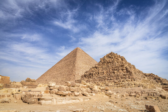View of the majestic pyramids rise from the golden sands under a vast blue sky dotted with clouds, Giza, Giza Governorate, Egypt.