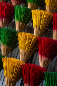 View of vibrant red, green, and yellow incense sticks create a mesmerizing pattern of color and texture, filling the frame with cultural richness, Hue, Vietnam.