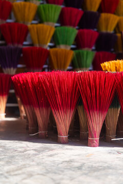 View of vibrant bundles of incense sticks, dyed in red, yellow, green, and purple hues, create a colorful display in Thuy Xuan Incense, Hue, Vietnam.