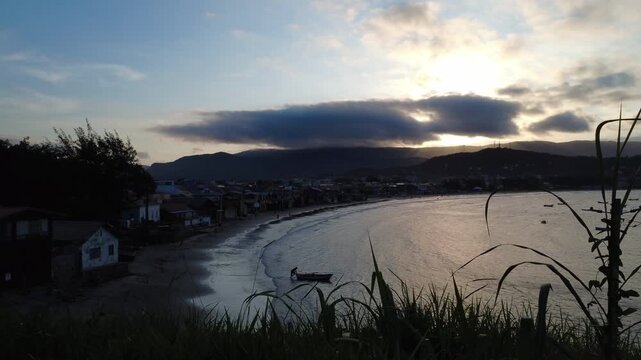 Late afternoon in a small fishing town. man pushes small fishing boat out to sea.