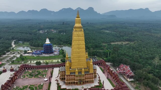 Aerial view of the golden Wat Maha That Wachiramongkol temple contrasting against the lush green forests, Kho Phi Phi Island, Thailand.