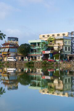 Hue City, Vietnam - 24 January 2026: View of vibrant buildings mirrored in the tranquil river, creating a harmonious blend of urban life and natural serenity.