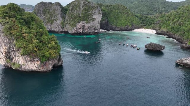 Aerial view of boats sailing on the serene turquoise water with rocky islands covered in lush green trees, Halong Bay, Vietnam.