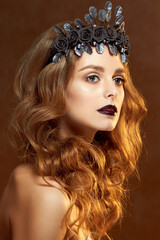 Fototapeta premium Close-up portrait of a beautiful young girl with a flower wreath in her hair. She wears a delicate flower crown with dark leaves. Beauty, spa, manicure and skin care concept