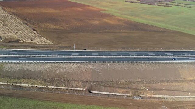 Sziksz&oacute;, Borsod-Aba&uacute;j-Zempl&eacute;n County, Hungary&mdash;an aerial, sideways tracking view of the M30 motorway traversing rural countryside with fields, asphalt pavement, barriers, and minimal traffic.