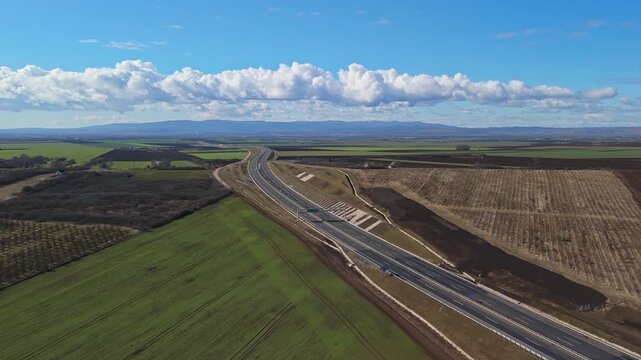 Sziksz&oacute;, Hungary&rsquo;s M30 motorway and interchange traverse green fields and rolling hills in Borsod-Aba&uacute;j-Zempl&eacute;n County, viewed from an elevated aerial perspective on a clear daytime.