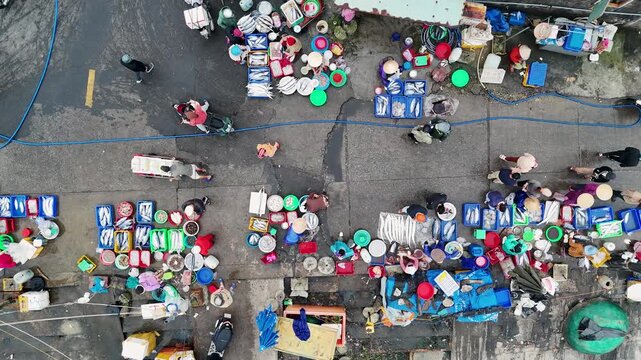Aerial view of a vibrant outdoor fish market bustling with activity, showcasing colorful containers and vendors displaying their fresh catches, Da Nang, Vietnam.