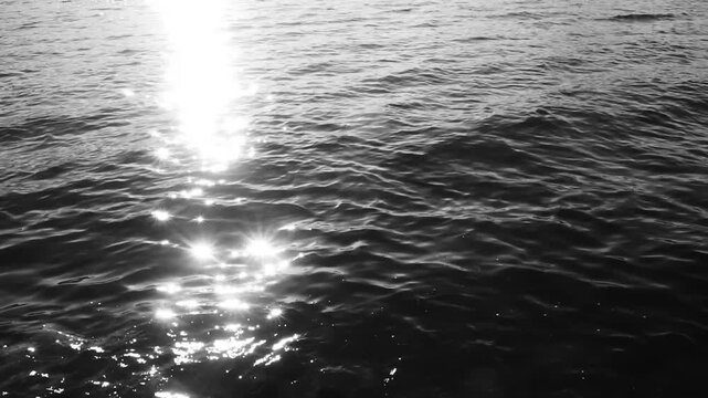 Close-up of bright sunlight reflections dancing on the gentle ripples of a dark sea surface. Chile, 4K