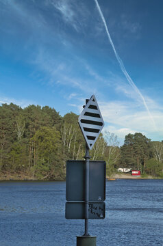 Rhombus shaped traffic sign located at a scenic lake with a forest background