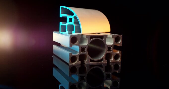 Stacked industrial silver aluminum t-slot and quarter round extrusion profiles on black background