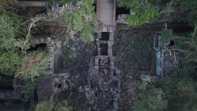 Aerial view of the ancient Beng Mealea Temple ruins, overgrown with lush green vegetation, revealing the temple's weathered stone structures, Beng Mealea, Cambodia.
