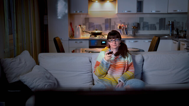 Woman Relaxing on Sofa at Home in Cozy Sweater with Glass of Win, have fun and enjoy