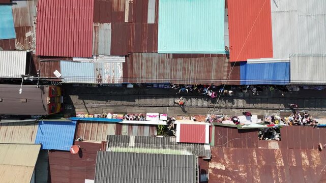Aerial view of the vibrant Maeklong Railway Market, where vendors sell goods along the train tracks amidst the colorful corrugated iron roofs, Maeklong, Thailand.