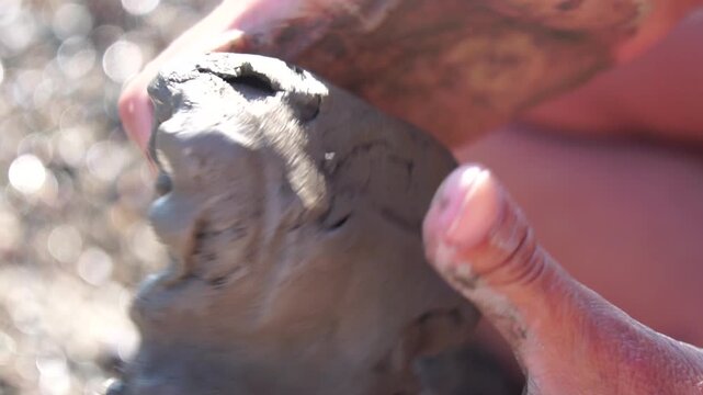 Clay hands molding, person shaping wet natural clay on sunny beach, creative sensory experience