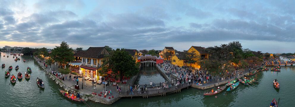 Aerial view of the vibrant Japanese Covered Bridge reflected on the serene river amidst the bustling Hoi An Ancient Town, Hoi An, Vietnam.