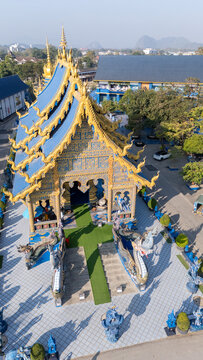 Aerial view of Wat Rong Suea Ten Temple with its striking blue and gold facade, a modern marvel amidst the serene landscape, Chiang Rai, Thailand.