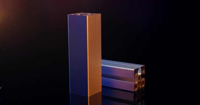 Standing silver aluminum extrusion profile with industrial t-slot rails and warm lighting on black background