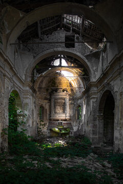View of sunlight pierces the skeletal remains of a forgotten church, illuminating patches of vibrant green moss clinging to weathered stone, Parma, Emilia Romagna, Italy.