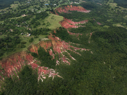 View of a dramatic canyon carved through vibrant green terrain, revealing striking red and white layers in Pointe Noire, Congo.