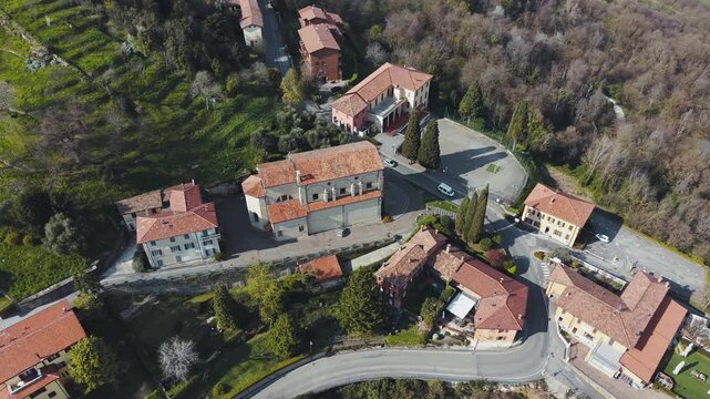 Aerial Drone Circular Flight Around Historic Stone Church in Montevecchia Hilltop Village with Vineyards Olive Groves and Italian Countryside Lombardy 4K