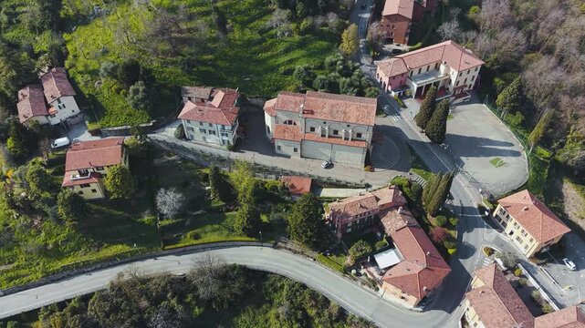 Cinematic Drone Orbit Shot Around Historic Church and Italian Village of Montevecchia with Terracotta Rooftops Vineyards and Green Hills Lombardy Italy 4K
