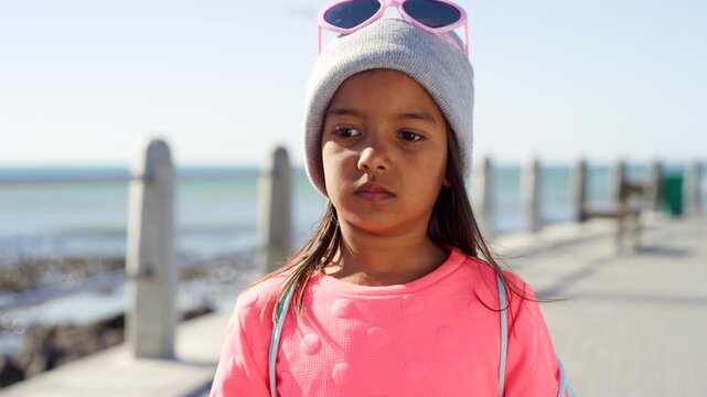 Beach, miserable and thinking with girl kid outdoor for holiday, travel or vacation frustration. Grumpy, moody and unhappy with thoughtful child on promenade for sightseeing or tourism disappointment