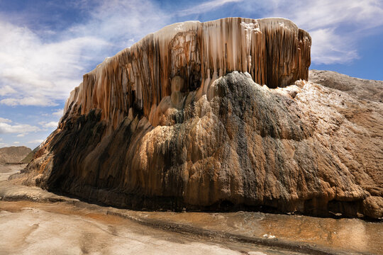 View of a striking rock formation with cascading mineral deposits under a blue sky, creating a unique geological spectacle, Annaba, Algeria.