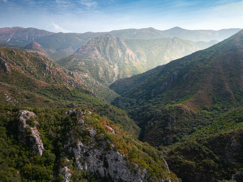 Aerial view of rugged mountains cloaked in emerald forests, where the Acheron river carves a path through the landscape, Preveza, Greece.