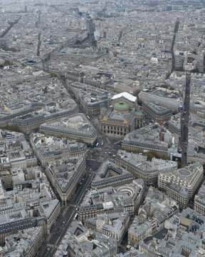 Aerial view of the intricate web of streets converging at the opulent Palais Garnier, its facade a beacon amidst the urban sprawl, Paris, France.