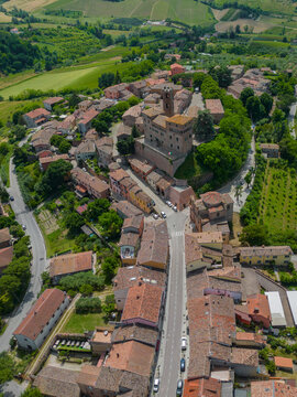 Aerial view of terracotta rooftops and ancient stone buildings nestled amid verdant trees, creating a harmonious blend of urban and natural beauty, Sorrivoli, Emilia Romagna, Italia.