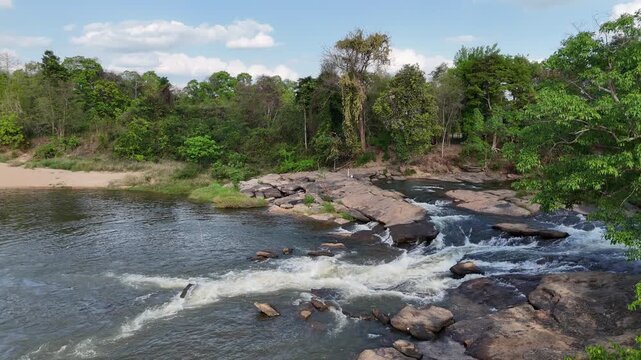 Aerial view of Kaeng Tana Pat rapid, lush green river flowing through forest, refreshing summer travel destination in Thailand