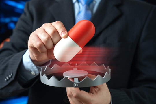 A man inserts a medication capsule into a trap. Drug addiction and medical collusion highlighting pharmaceutical abuse regulatory failure and healthcare ethics concerns.