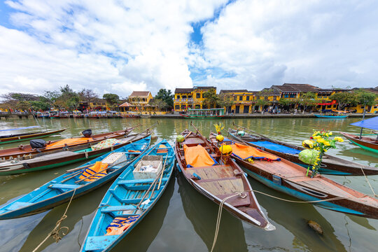Hoi An, Vietnam - 28 January 2026: View of colorful boats bobbing gently on the reflective waters of the canal, framed by the vibrant yellow buildings of the Old Town.