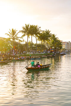 Hoi An, Vietnam - 28 January 2026: View of a boat gliding along the tranquil river, reflecting the golden sunset hues and the vibrant life of the Lantern Bridge.