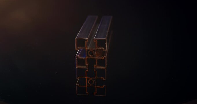 Extruded aluminum t-slot profile rail with blue and orange light reflections on black surface