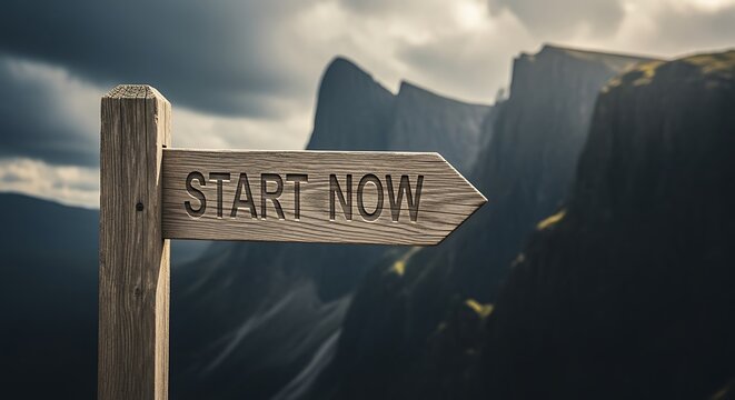 Wooden signpost with start now arrow pointing to the right in mountains