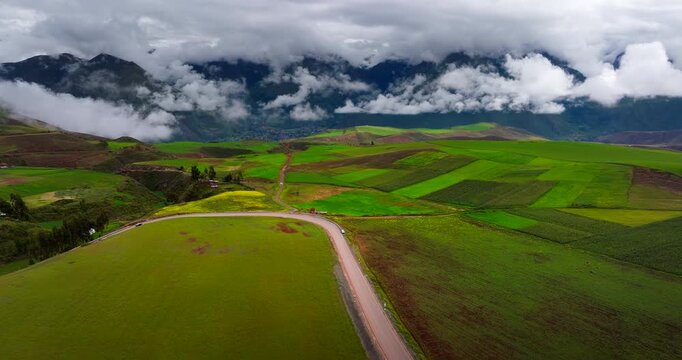 Green agricultural fields and winding rural road in Maras district Sacred Valley Peru, aerial panoramic establishing backdrop