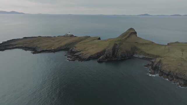 Cinematic aerial clip of Neist point lighthouse located on the rugged cliffs the Isle of Skye during a dramatic sunset.