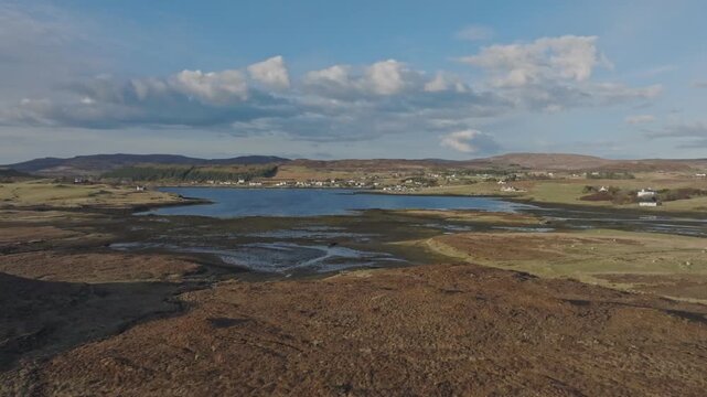 Fast flying drone flight over a vast cracked dried lake bed on a hot sunny day with small remote village a far distance