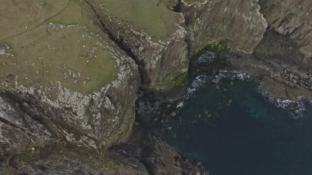 Cinematic bird eye aerial view of sharp cliffs facing an ocean with blue water in Scotland, 4K 60fps with DJI Mavic pro Drone