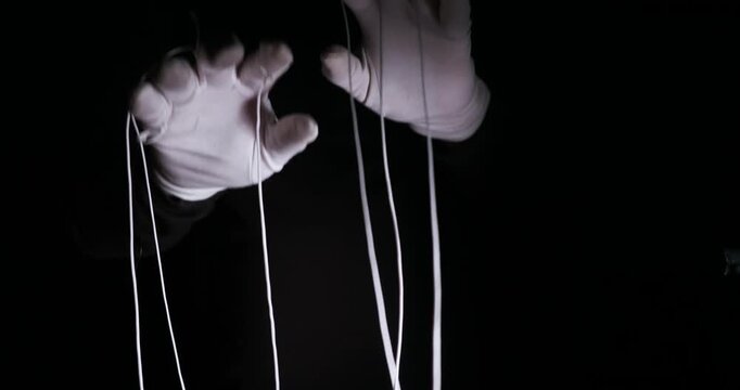 White gloved hands manipulating strings on black background, Symbolizes political control, authority, and the "Puppet Master" power metaphor.