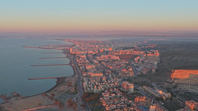 Golden hour light illuminating the cityscape of santa pola. Aerial perspective capturing the beautiful coastline and urban development in alicante