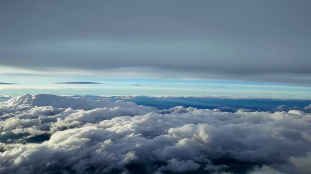 Hyperlapse captured from a jet cockpit accelerated x5 while flying at dawn between layers of clouds illuminated by soft sunflght.