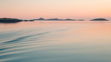 Fototapeta premium Tranquil sea view at sunrise with gentle waves and soft pink orange hues reflecting on the water Distant islands are faintly visible on the horizon creating a peaceful serene scene
