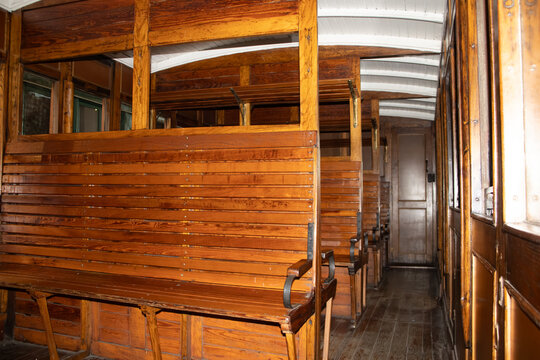 Interior de vag&oacute;n de tren antiguo con asientos de madera y pasillo estrecho, evocando transporte hist&oacute;rico, dise&ntilde;o cl&aacute;sico y viajes de &eacute;poca en ferrocarril.