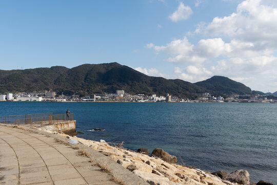 Panoramic view of Mojiko waterfront and mountains across the blue sea from Ganryujima Island under a blue sky.