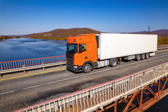 Orange truck on a bridge over the river