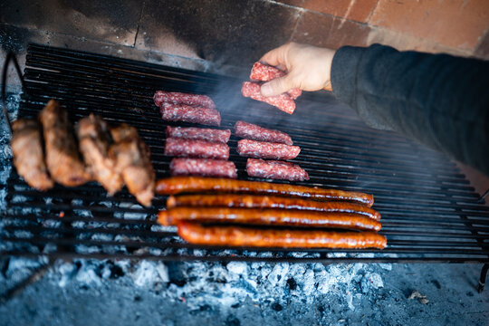 Hand grilling meat and sausages on a barbecue