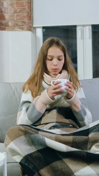 Portrait of upset ill teenager person with light long hair which cought cold and is treated at home ,drinking freshly brewed medicinal tea,coughing and feeling not good during sickness